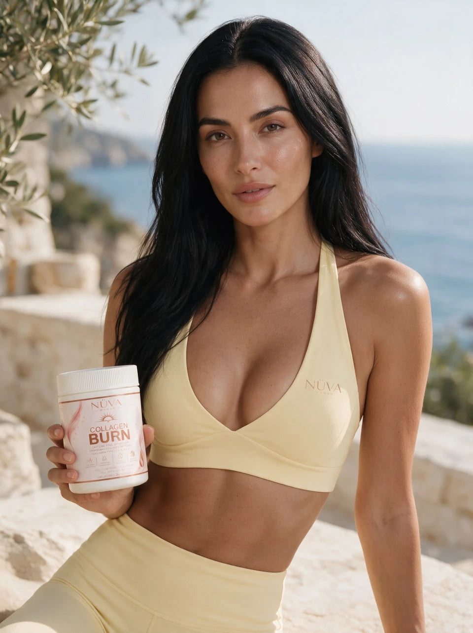 Woman in a pale-yellow NÜVA WOMAN outfit holding the owner-supplied Collagen Burn jar on a coastal terrace